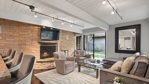 A modern living room with a stone fireplace, leather sofas, a glass coffee table, and a large mirror. - Aspen Alps Apartment #107 2 Bedroom Condo by RedAwning (Aspen)