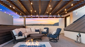 Um terraço no telhado com lareira, mobiliário de exterior e vista para o pôr do sol.