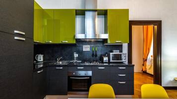 A modern kitchen with dark cabinetry, a stainless steel range hood, and a microwave.