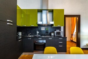 A modern kitchen with dark cabinetry, a stainless steel range hood, and a microwave. - Ca' Sant'Angelo (Venice)