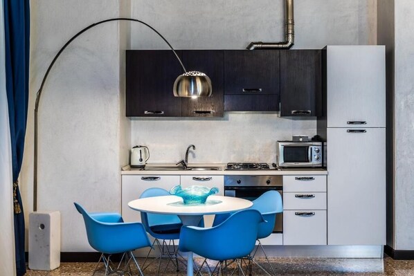 Una cocina moderna con una mesa redonda y sillas azules, un microondas y una estufa a gas.