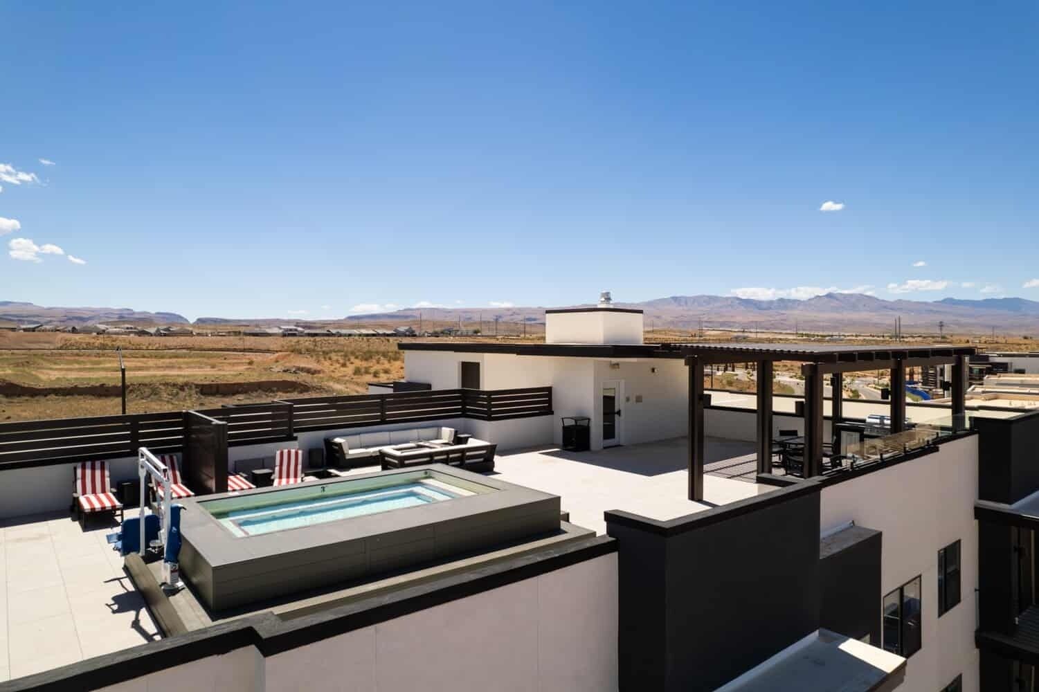 A rooftop pool area with a view of mountains, a covered seating area, and a modern architectural design.