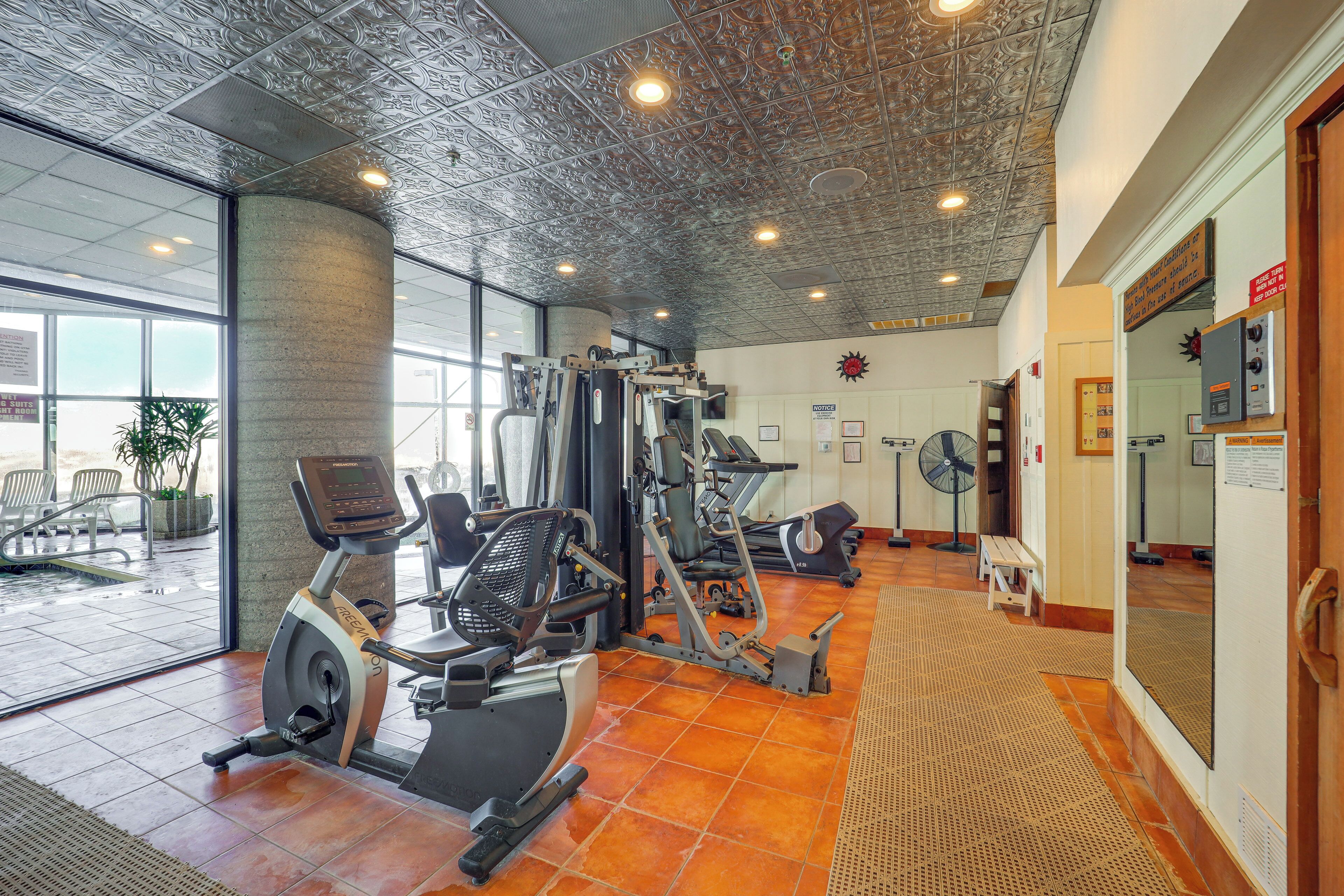 Ein Fitnessraum mit Trainingsgeräten, einem großen Fenster und einem Spiegel an der Wand.