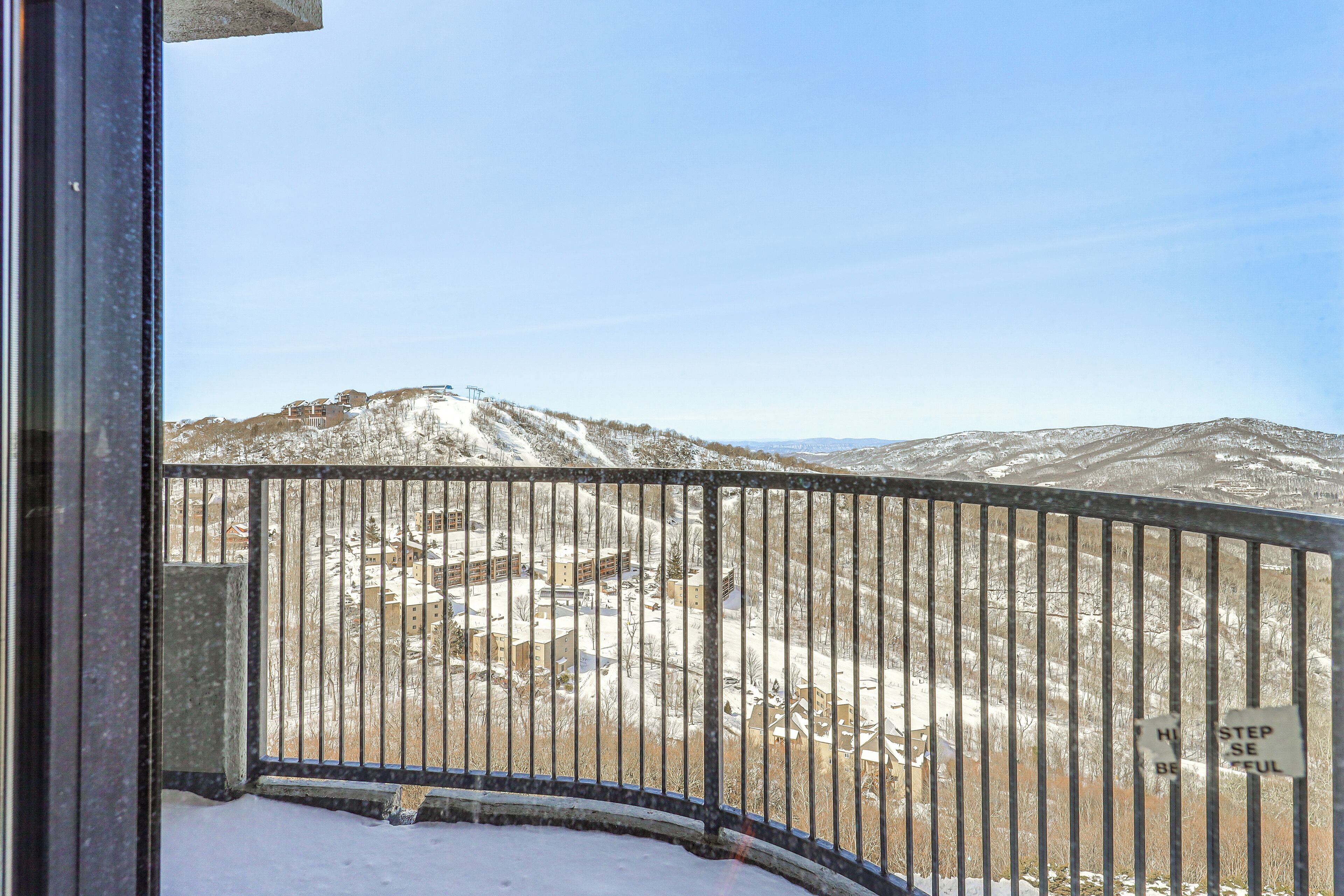 A snowy mountain landscape with a metal railing and a sign that reads "HILL STEP SE EFFUL."
