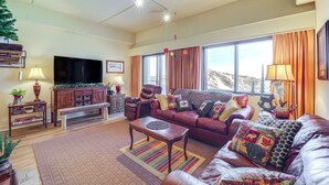 A living room with a leather sofa, a wooden coffee table, a flat-screen TV, and a large window with curtains. - 3 Mi to Sugar Mtn Slopes! Condo w/ Hot Tub & Pool (Banner Elk)