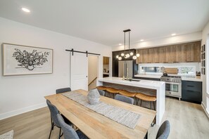 A modern kitchen with a central island, wooden cabinets, and a stainless steel refrigerator. - Fennville Vacation Rental: Seasonal Heated Pool! (Fennville)