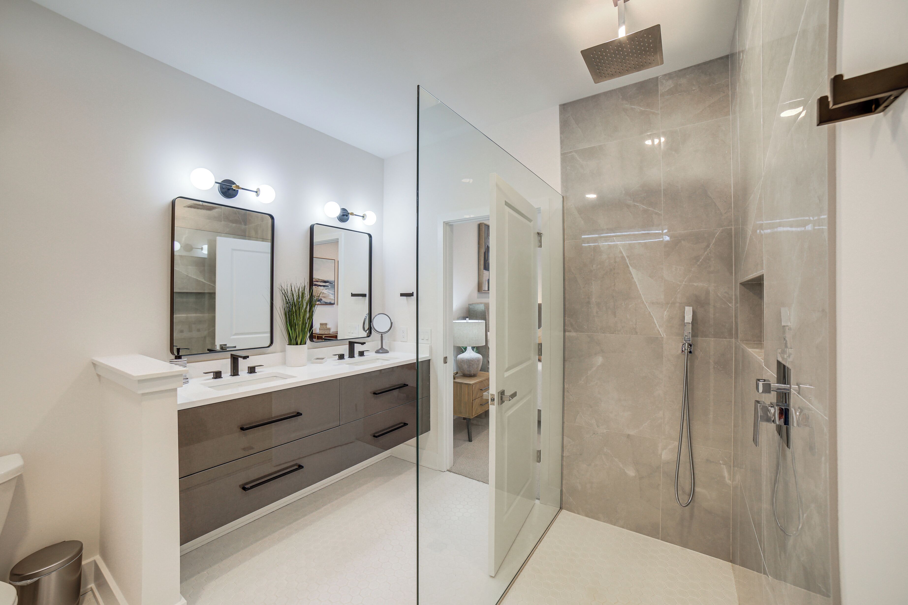 A modern bathroom with a glass-enclosed shower, a double vanity with a large mirror, and a white sink.
