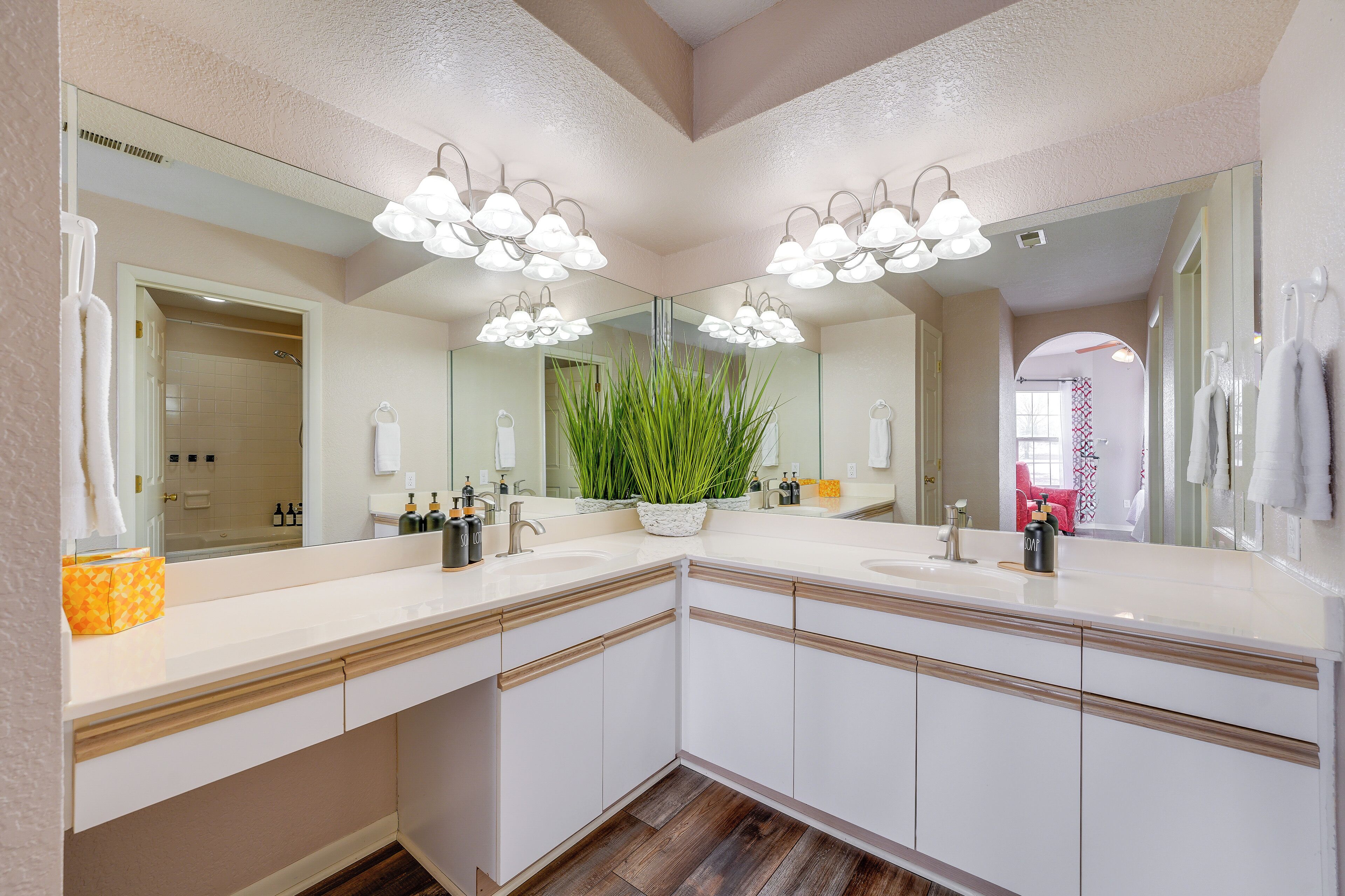Une salle de bain moderne avec un grand miroir, deux vasques et une plante en pot.