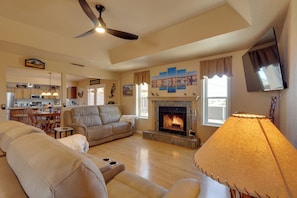 A living room with a fireplace, a ceiling fan, and a television mounted on the wall. - Furnished Patio, Grill & Views: Lake Havasu Home (Lake Havasu City)