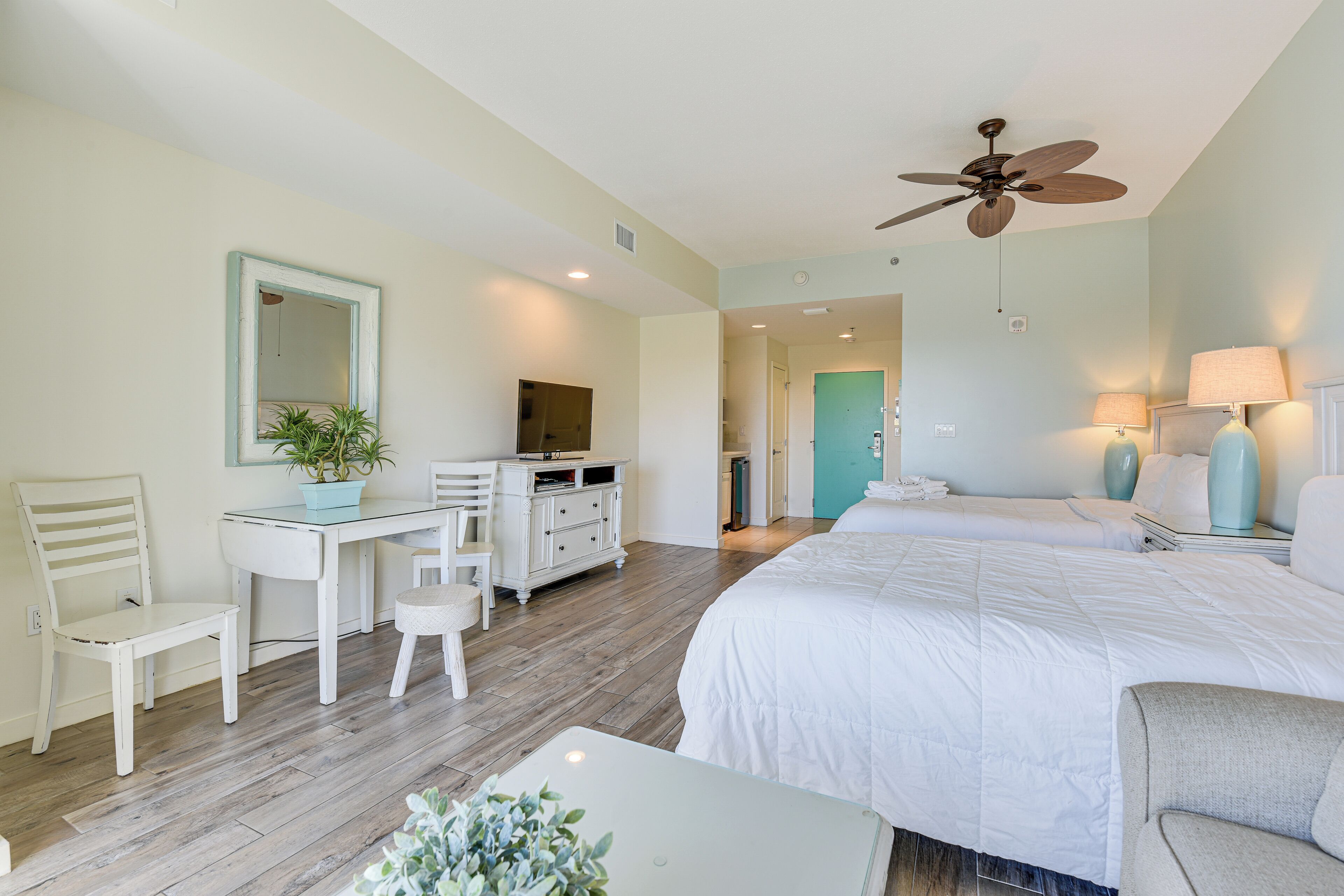 Une chambre à coucher comprenant un lit, un bureau, une chaise et un ventilateur de plafond.