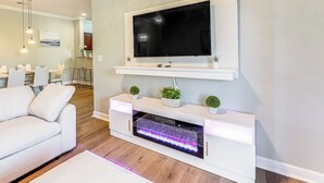 Ein modernes Wohnzimmer mit Flachbildfernseher, weißem Unterhaltungsschrank und einem weißen Sofa.