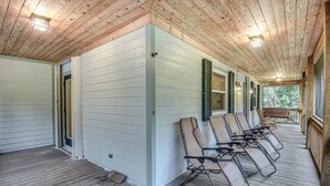A covered porch with wooden flooring and a row of lounge chairs.