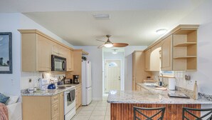 A kitchen with wooden cabinets, a granite countertop, a built-in oven, and a ceiling fan.