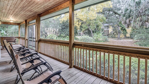 A covered porch with wooden railings and a view of the surrounding trees.