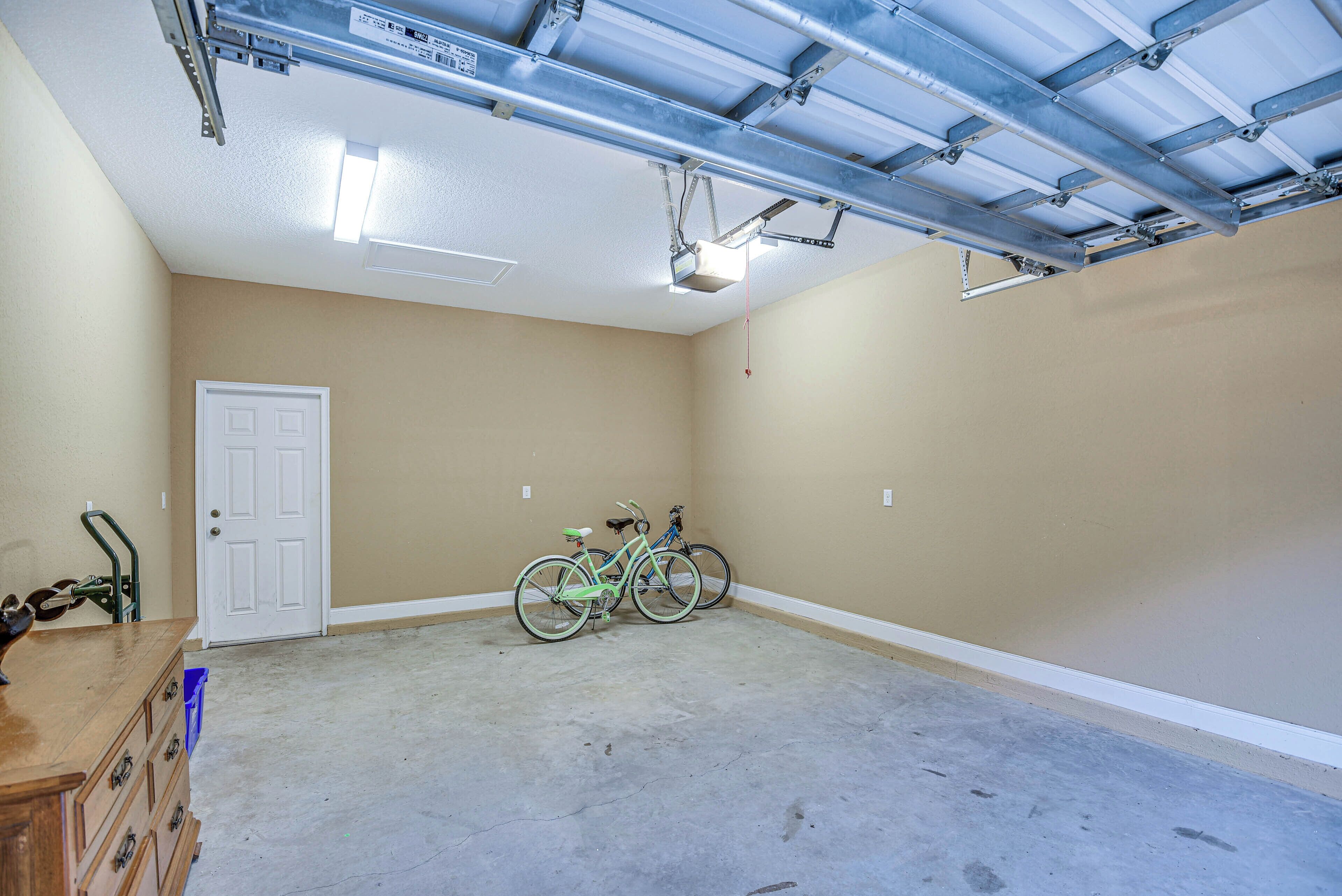 A garage with beige walls, a white door, and two bicycles.