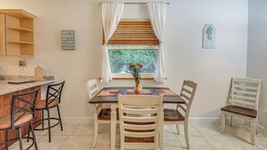 A dining area with a wooden table, four chairs, and a window with curtains.