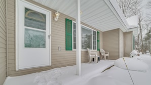 A house with a covered porch, a white door, and green shutters. - Cozy Mancelona Home: Ski, Golf & Snowmobile! (Mancelona)