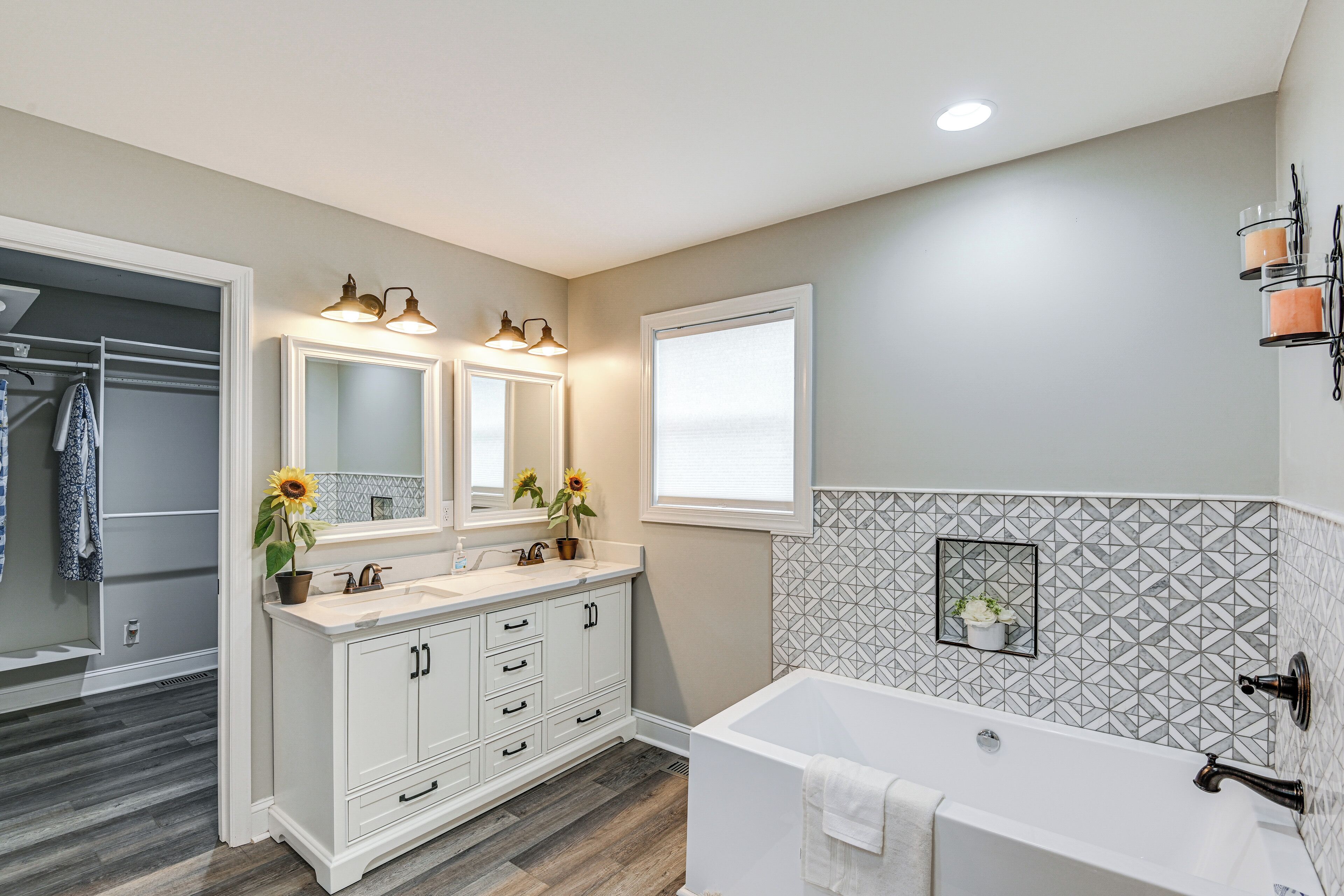A bathroom with a double sink vanity, a bathtub, and a mirror with lights.