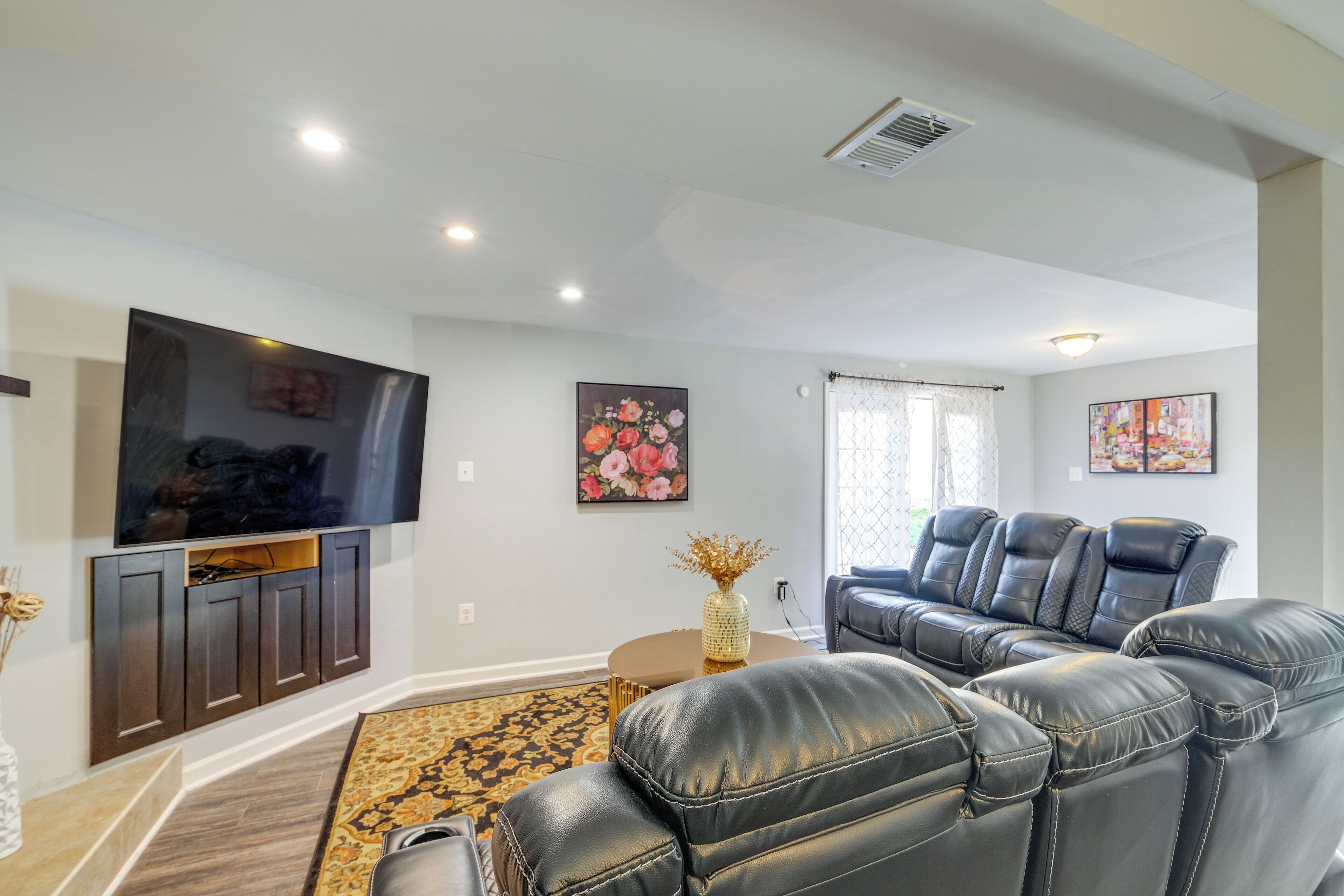 A living room with a flat-screen TV, leather recliners, a coffee table, and artwork on the walls.