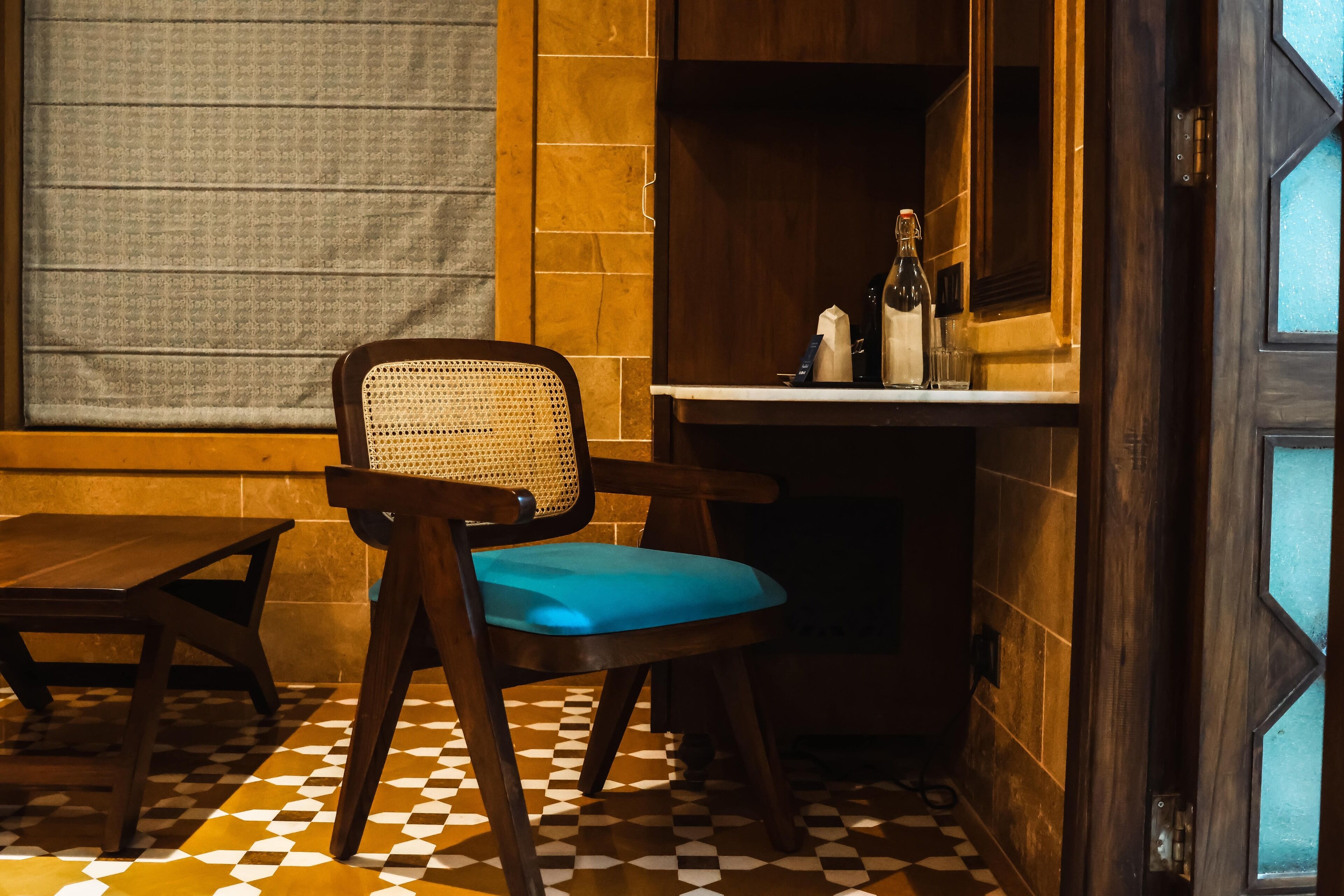A corner room with a wooden chair, a small table, and a tiled floor.