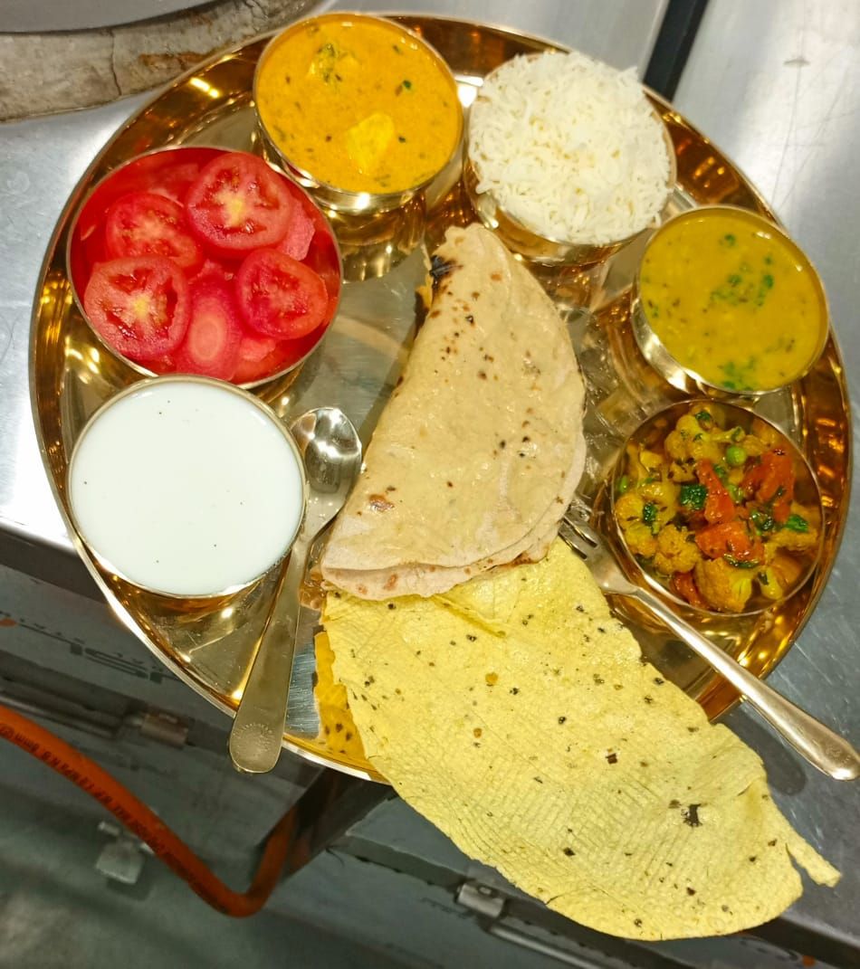 A meal served on a traditional Indian plate with various dishes including rice, curry, and flatbread.