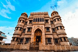 Un edificio grande y ornamentado con una entrada central en arco y múltiples balcones.