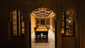 A corridor with a tiled floor, a central table, and ornate wall decorations.
