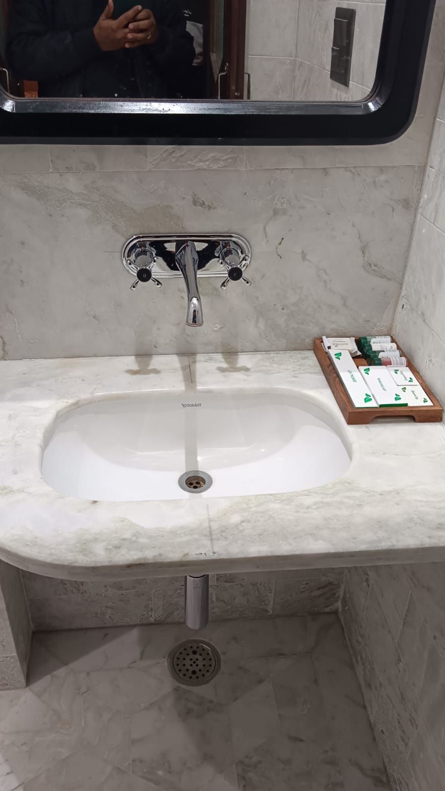 Un baño con un lavamanos blanco, grifo cromado y un espejo encima.