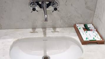 Un baño con un lavamanos blanco, grifo cromado y un espejo encima.