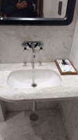 Un baño con un lavamanos blanco, grifo cromado y un espejo encima.