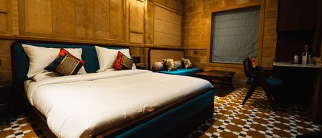 A hotel room with a large bed, a desk, and a chair. The room has a checkered floor and wooden walls.