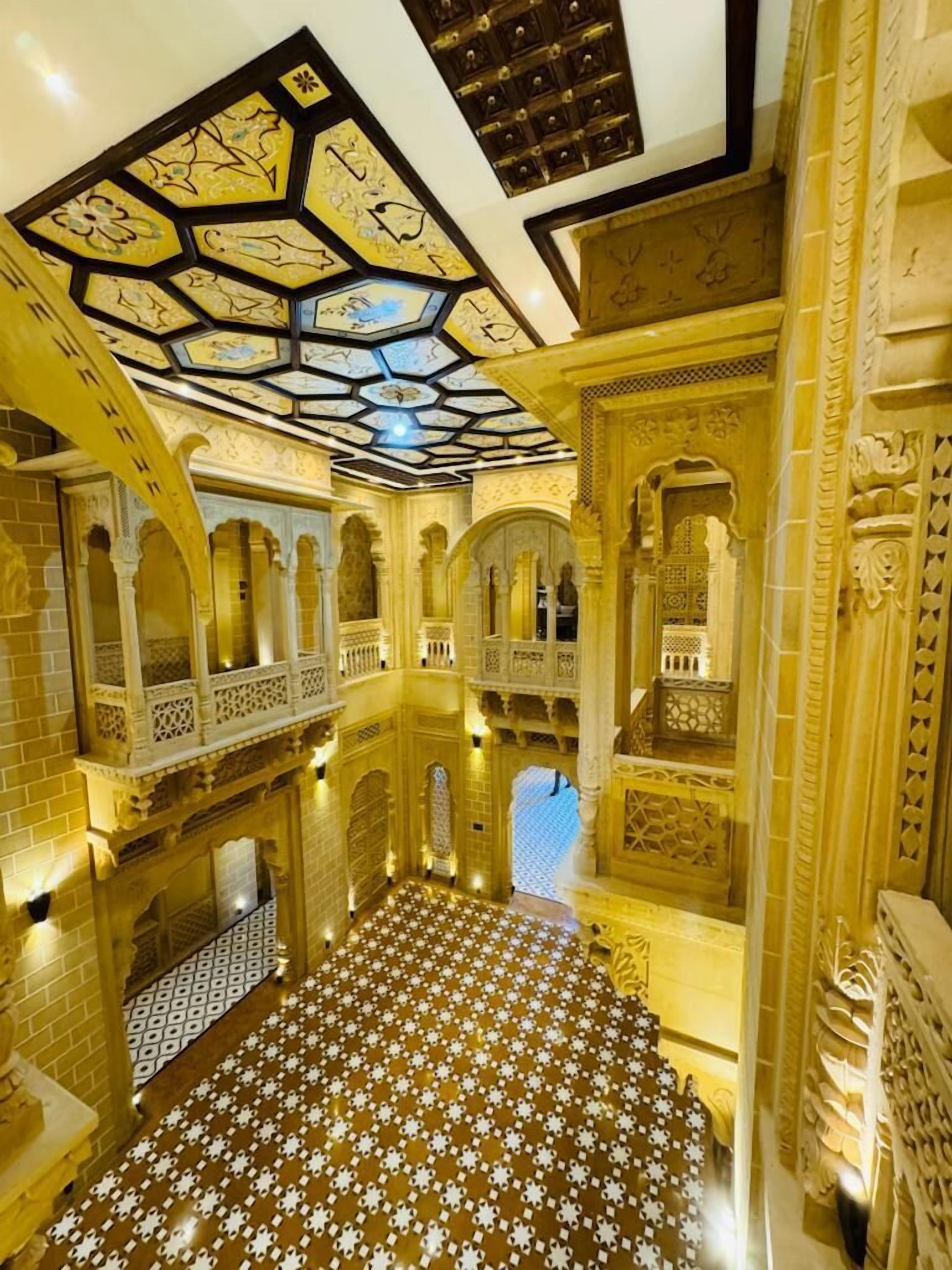 A grand interior with ornate arches, a patterned floor, and a ceiling with geometric designs.
