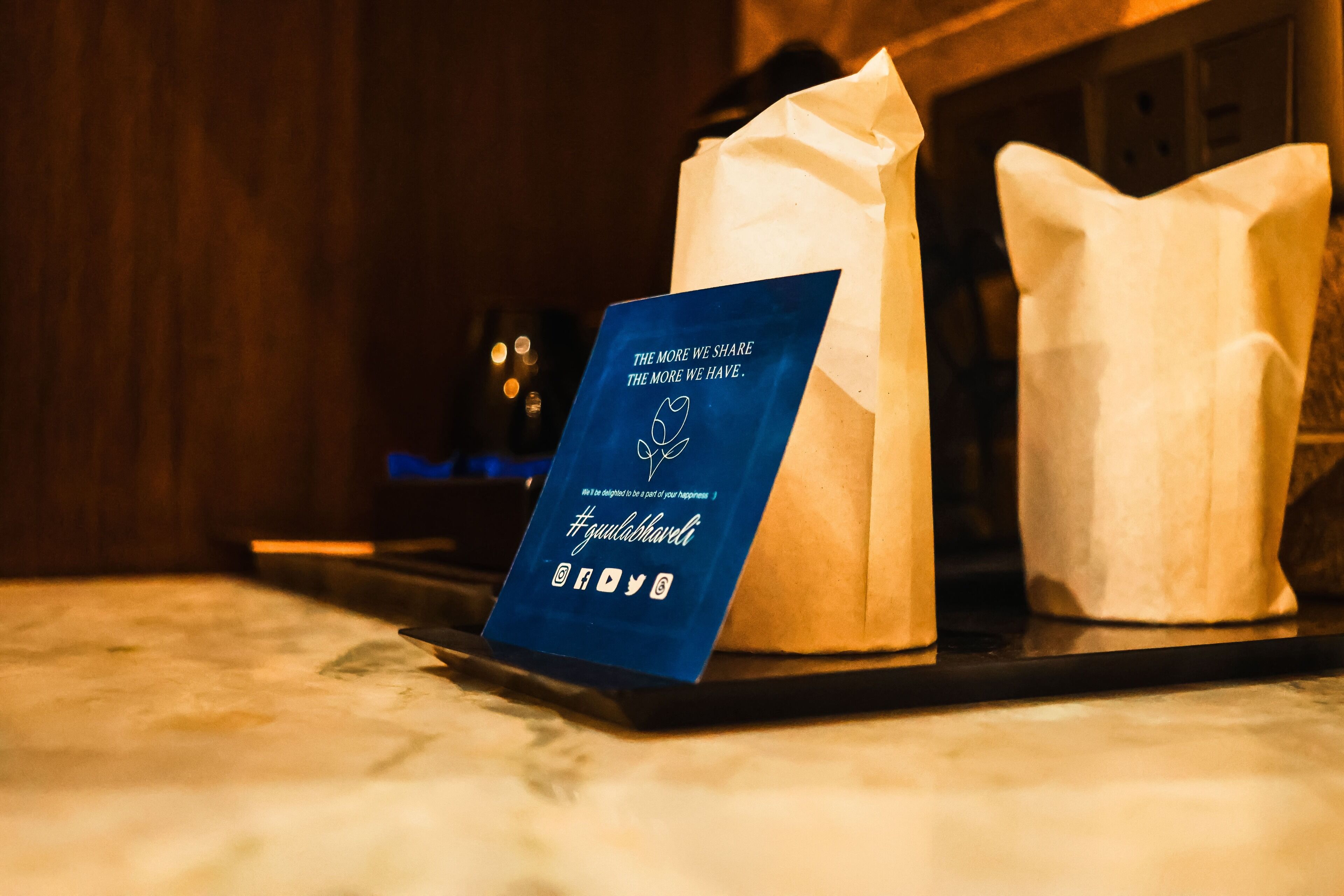 A tray with a blue card and two paper bags on a marble surface.