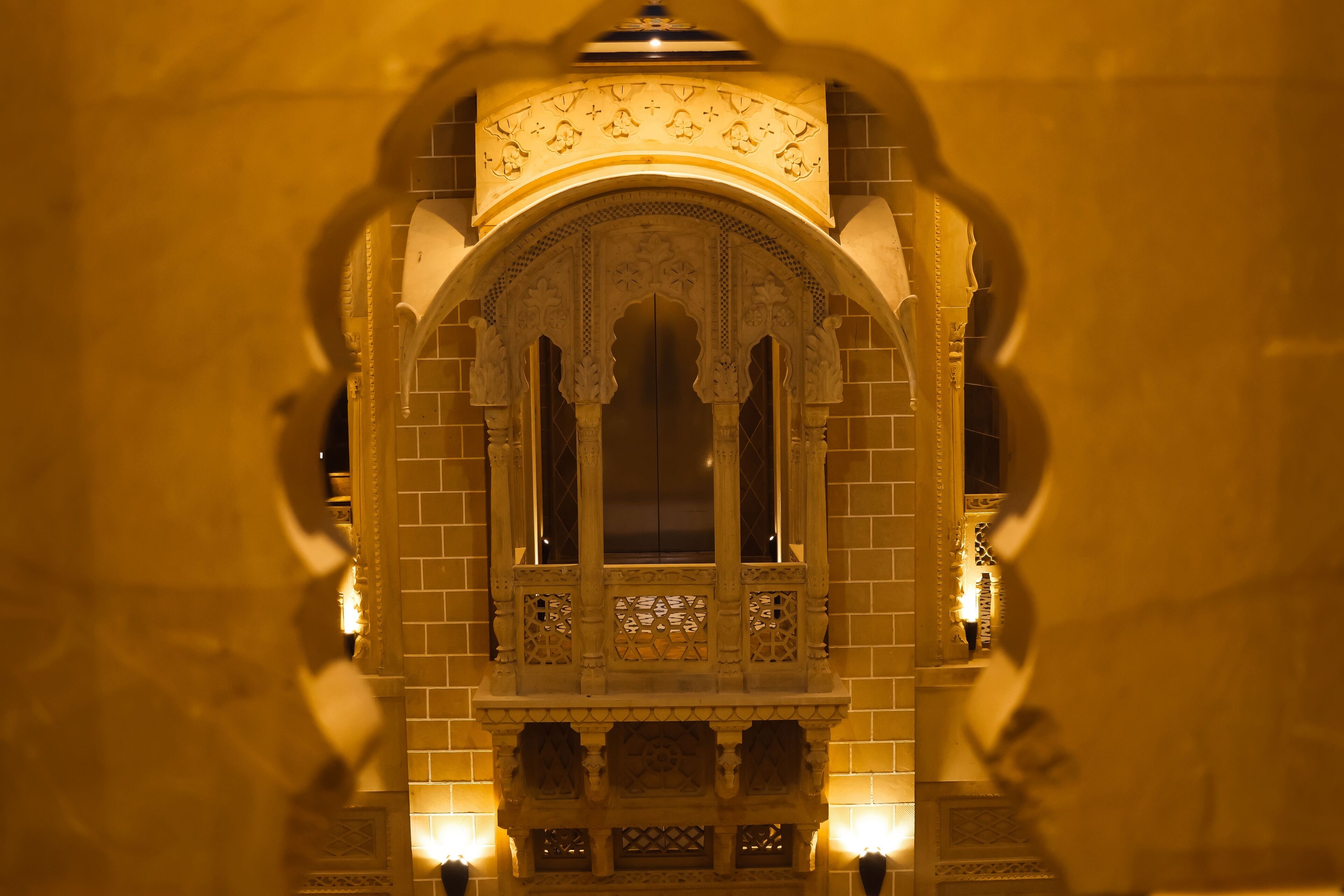An ornate architectural structure with intricate carvings and a symmetrical design, featuring a central arched window and decorative elements on the sides.