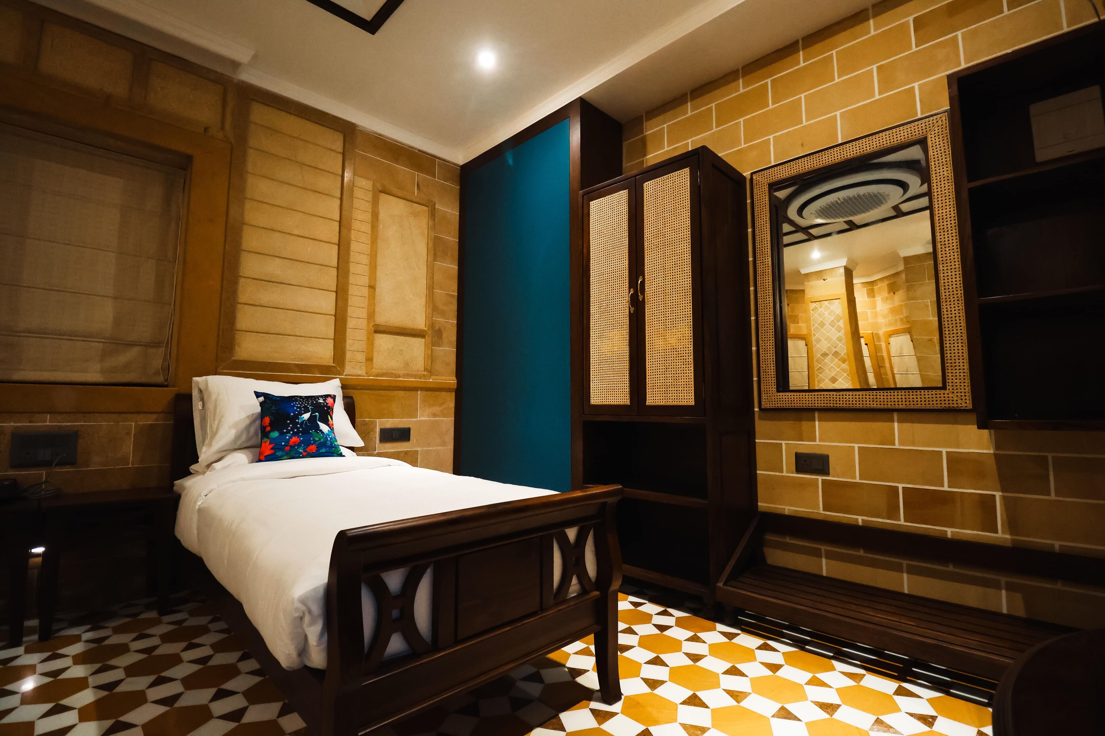 Une chambre d’hôtel avec un lit, un bureau, une armoire et un miroir.