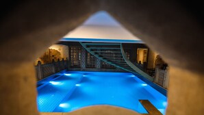 A swimming pool with blue lighting, a staircase, and a view of a building with intricate designs.