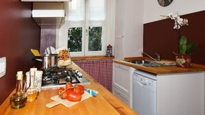 A compact kitchen with a gas stove, a sink, and a dishwasher. There is a window with a view of greenery outside. - Little Broggi - 15mins walking from Central Station. (Milano)
