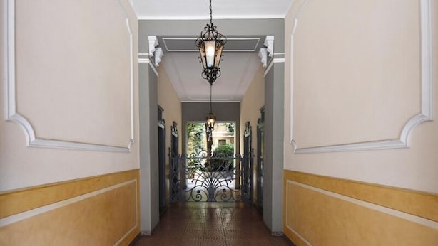 A hallway with a patterned floor, white walls with yellow trim, and a hanging light fixture. - Little Broggi - 15mins walking from Central Station. (Milano)