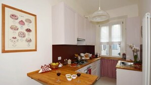 A compact kitchen with a wooden island, white cabinets, and a hanging light fixture. - Little Broggi - 15mins walking from Central Station. (Milano)