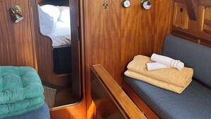 Een klein, houten interieur met een bed, een tafeltje en een bank.