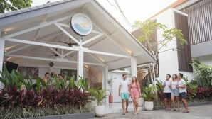 A covered outdoor area with a sign reading "Summer of Surf" and a group of people standing around. - Summer of Surf Hostel Uluwatu (Ungasan)