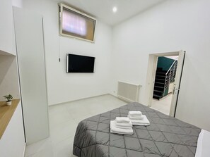 Un dormitorio con cama, televisor, radiador y escalera.