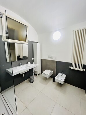 Un baño moderno con un espejo grande, dos lavamanos, un inodoro y un radiador.
