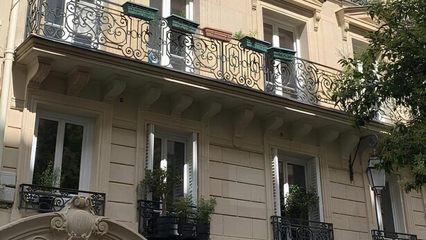 A multi-story building with ornate balconies and a storefront labeled "PROS HAIR." - Spacious Stunning 6th Floor Apartment in Renovated "Haussmannian" Building (Paris)