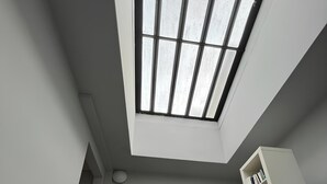 A modern loft bedroom with a skylight, a built-in bookshelf, and a wooden bench. - Spacious Stunning 6th Floor Apartment in Renovated "Haussmannian" Building (Paris)
