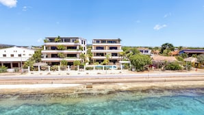 Un hotel frente a la playa con varios balcones, piscina y vista despejada del océano.