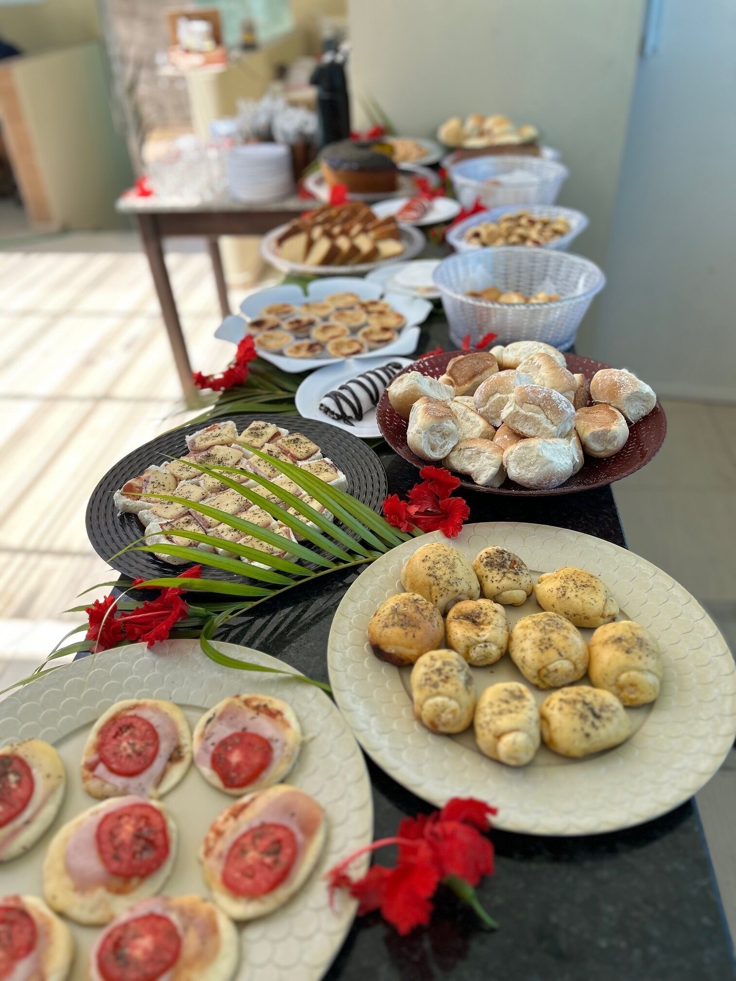 Una mesa de buffet con diversos alimentos, incluyendo pasteles, pan y un plato con rodajas de tomate.