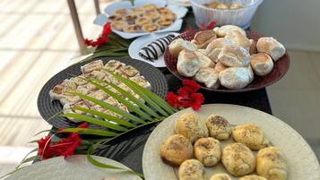 Una mesa de buffet con diversos alimentos, incluyendo pasteles, pan y un plato con rodajas de tomate.
