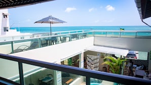 A balcony with a view of the ocean, a pool, and outdoor seating. - Pousada Ondas do Mar (Ipojuca)