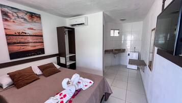A hotel room with a bed, a wardrobe, a bathroom with a sink and mirror, and a painting on the wall.